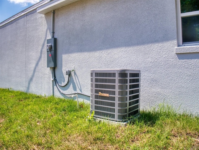details featuring electric meter, stucco siding, and cooling unit