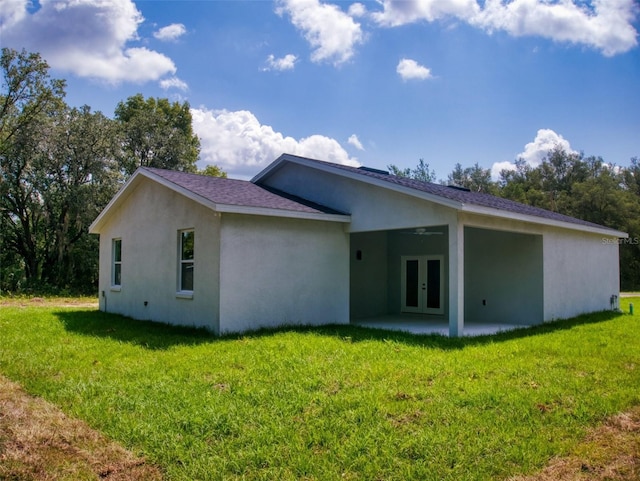 back of house featuring a patio area, a lawn, stucco siding, french doors, and roof with shingles