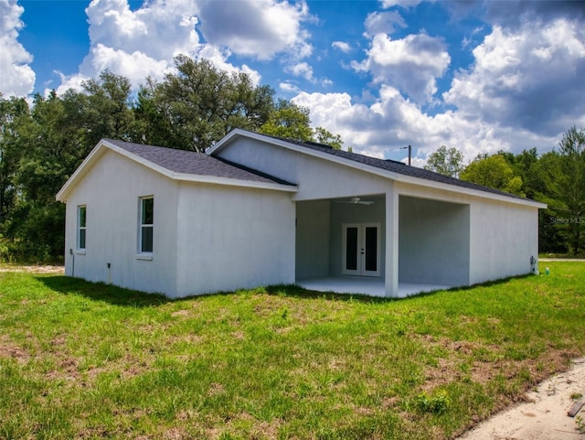 back of property with a yard, french doors, a ceiling fan, and a patio area