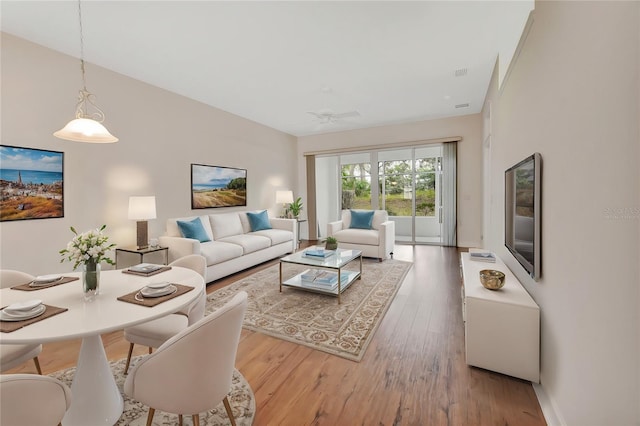 living area with a ceiling fan, visible vents, and wood finished floors