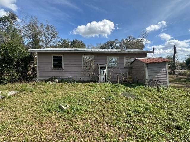 rear view of property featuring a storage unit and a lawn