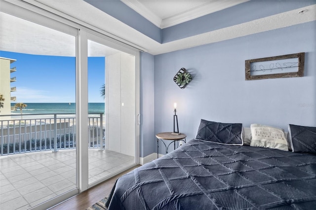 bedroom featuring a water view, wood-type flooring, ornamental molding, a beach view, and access to outside