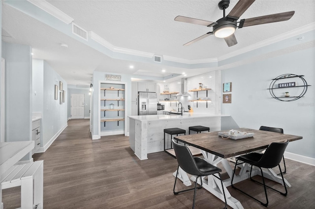 dining room with a raised ceiling, ornamental molding, sink, and dark hardwood / wood-style flooring