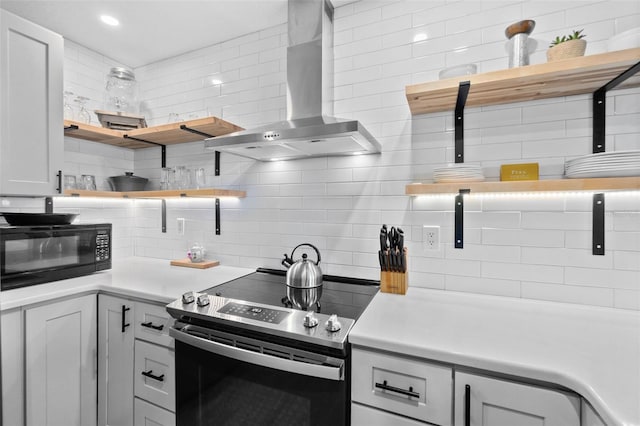 kitchen with tasteful backsplash, white cabinetry, wall chimney range hood, and stainless steel range with electric cooktop