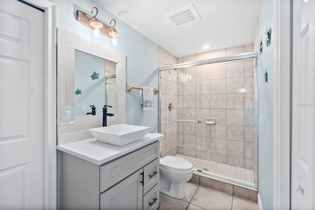 bathroom with tile patterned flooring, vanity, a shower with shower door, and toilet