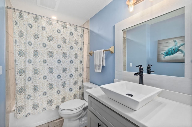 full bathroom with shower / tub combo with curtain, vanity, tile patterned flooring, and toilet