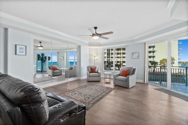 living room with crown molding, wood-type flooring, a textured ceiling, and plenty of natural light