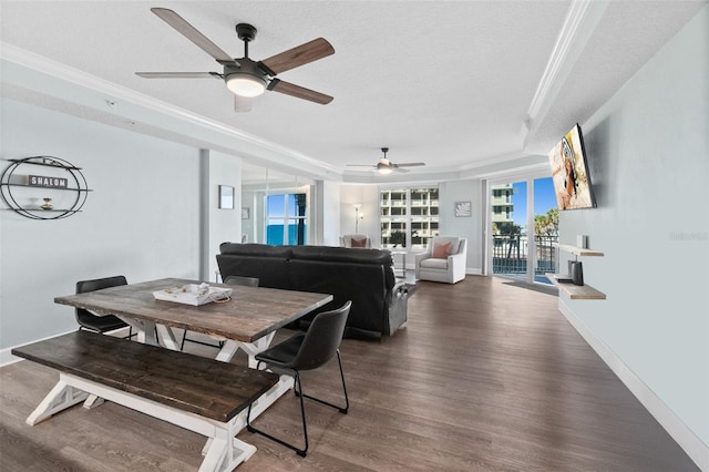 dining room with a tray ceiling, crown molding, dark hardwood / wood-style floors, and a textured ceiling