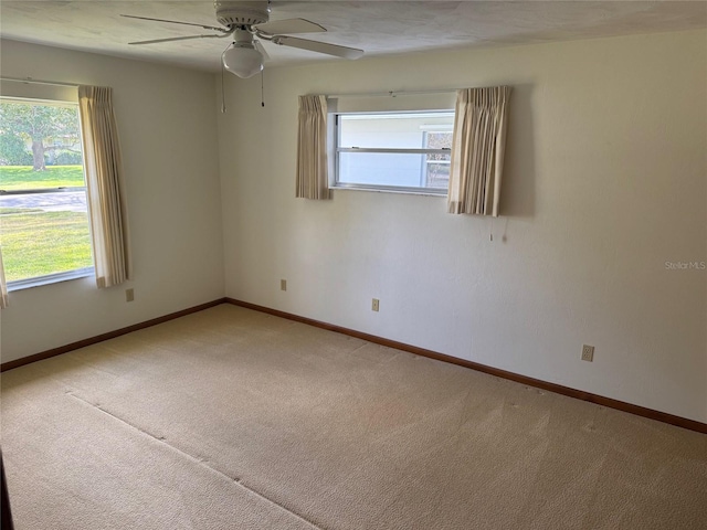 empty room with baseboards, ceiling fan, and light colored carpet