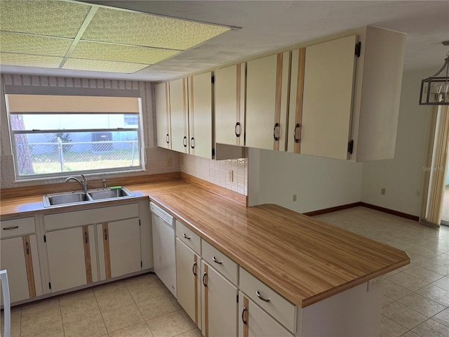 kitchen with light tile patterned floors, backsplash, white dishwasher, a sink, and baseboards