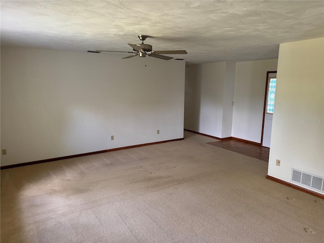 carpeted spare room featuring ceiling fan, a textured ceiling, visible vents, and baseboards