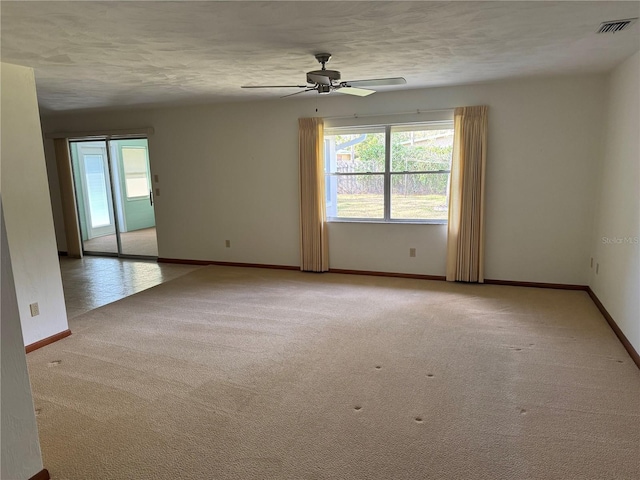 empty room featuring light colored carpet, visible vents, baseboards, and a textured ceiling