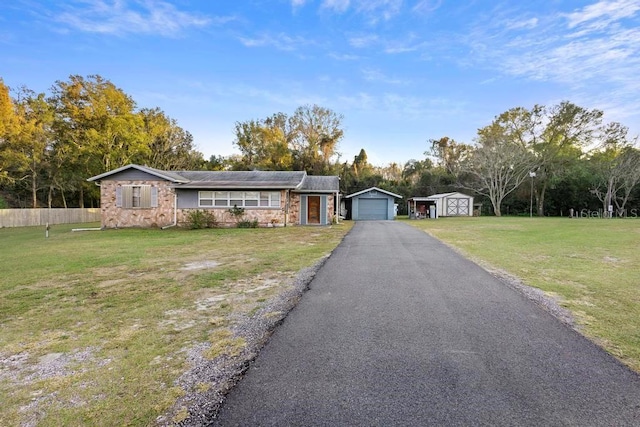 single story home featuring a storage shed, a garage, and a front yard