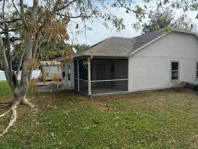 rear view of property featuring a sunroom, a lawn, and a patio area