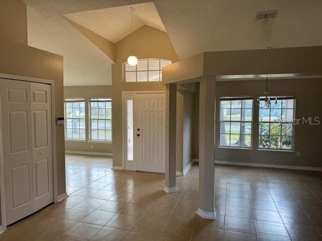 foyer entrance with lofted ceiling, a textured ceiling, and light tile patterned floors