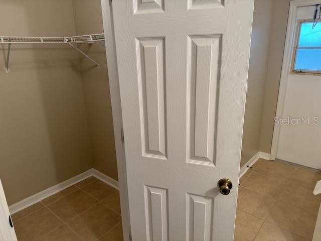 walk in closet with light tile patterned floors