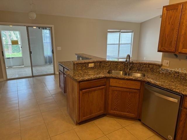 kitchen with a wealth of natural light, sink, stainless steel dishwasher, and dark stone counters