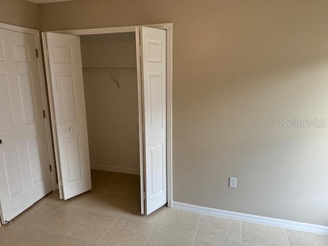 unfurnished bedroom featuring light tile patterned floors and a closet