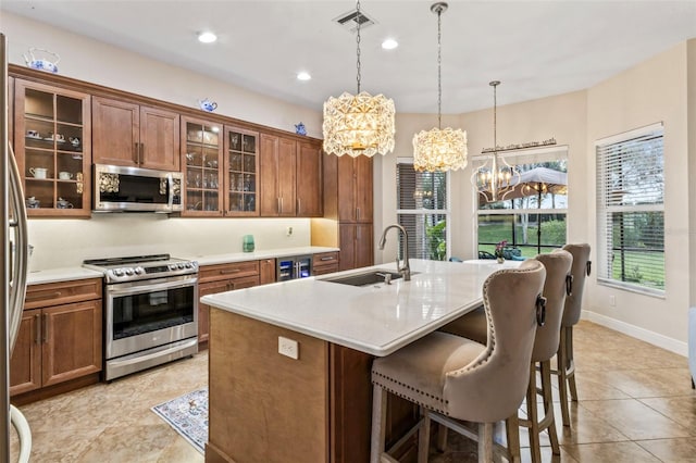 kitchen with sink, decorative light fixtures, stainless steel appliances, an island with sink, and a breakfast bar area