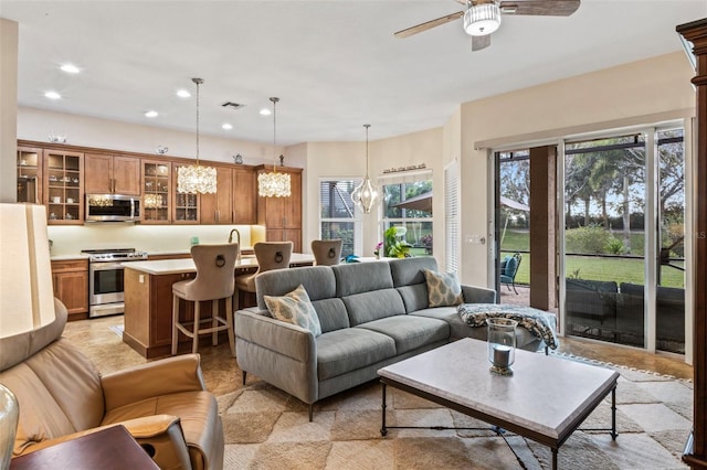 living room with sink and ceiling fan with notable chandelier