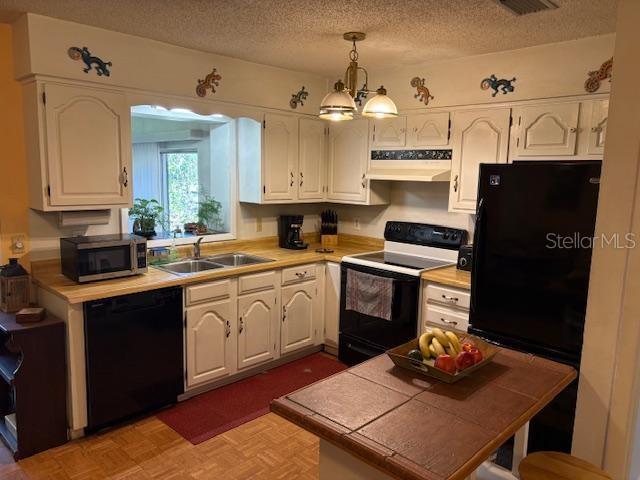 kitchen with sink, decorative light fixtures, black appliances, and white cabinets