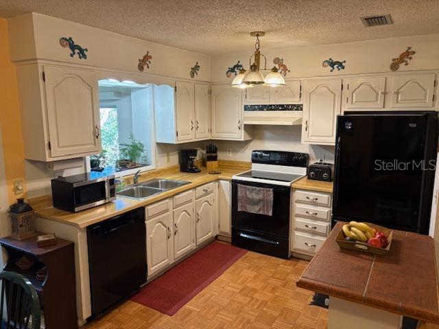 kitchen with pendant lighting, sink, black appliances, a textured ceiling, and white cabinets