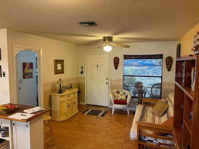 foyer with parquet floors, a textured ceiling, and ceiling fan