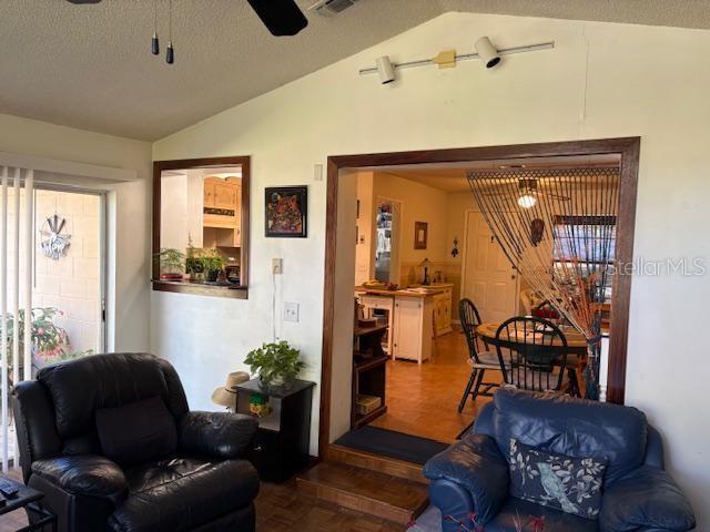 living room featuring lofted ceiling, parquet floors, a textured ceiling, and ceiling fan