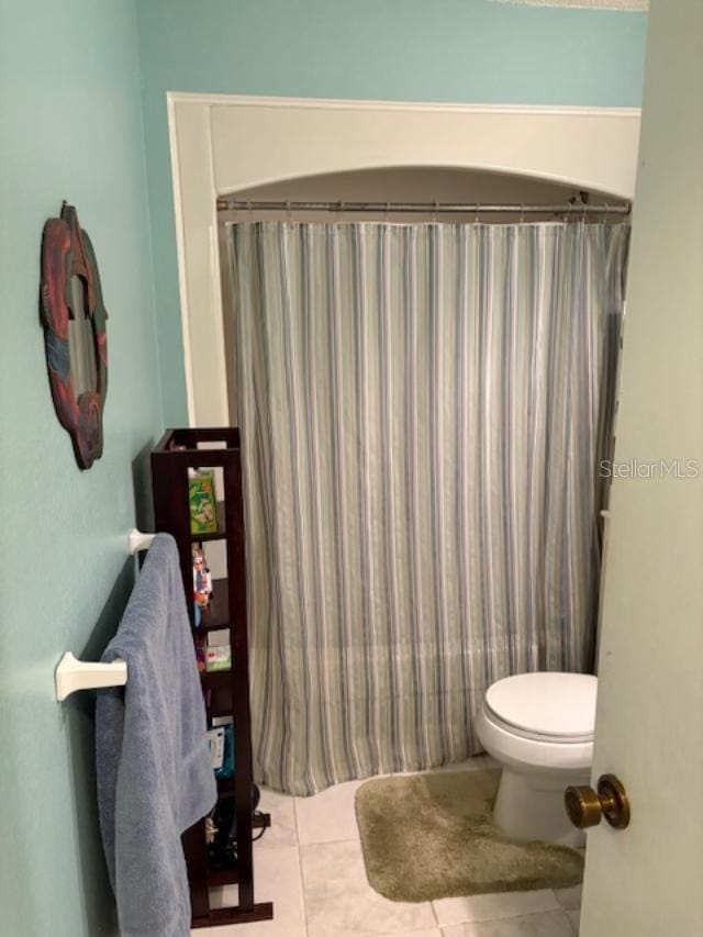 bathroom with tile patterned flooring, toilet, and shower / tub combo with curtain