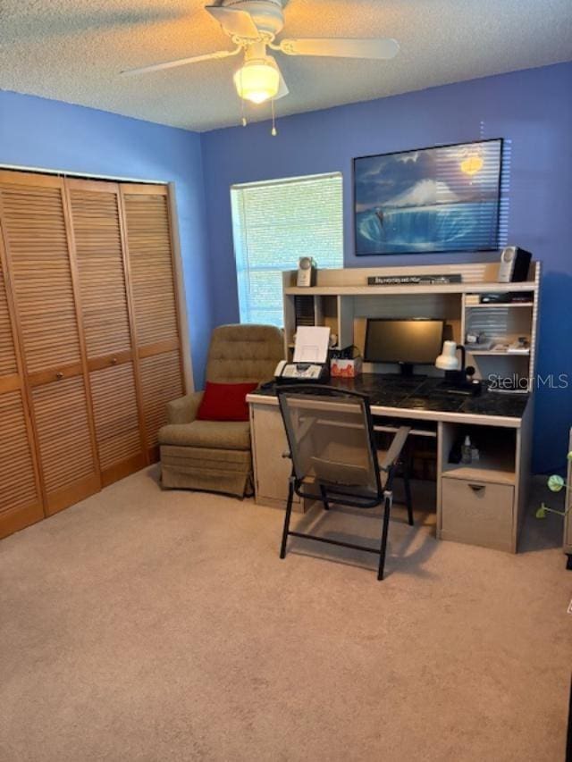 carpeted home office featuring ceiling fan and a textured ceiling