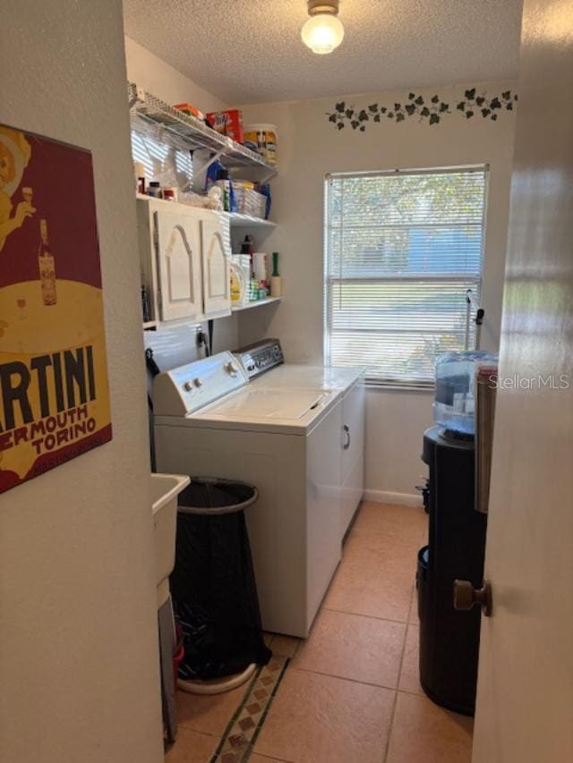 washroom featuring light tile patterned floors, a textured ceiling, cabinets, and washing machine and clothes dryer