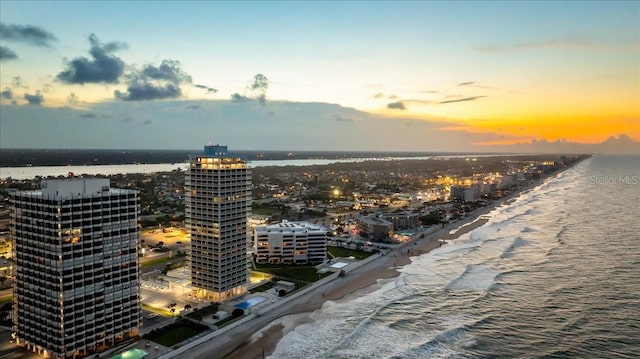 aerial view at dusk with a water view and a beach view