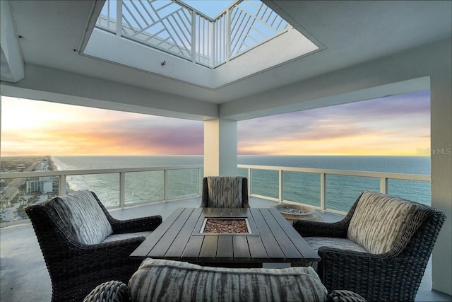 balcony at dusk featuring a fire pit and a water view