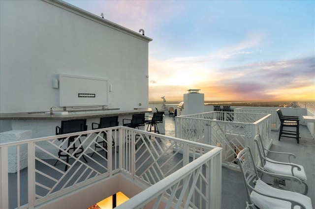 balcony at dusk featuring exterior bar