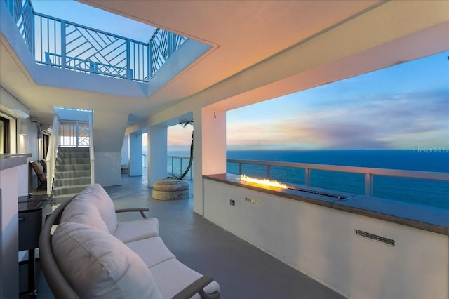 balcony at dusk featuring a water view and an outdoor hangout area