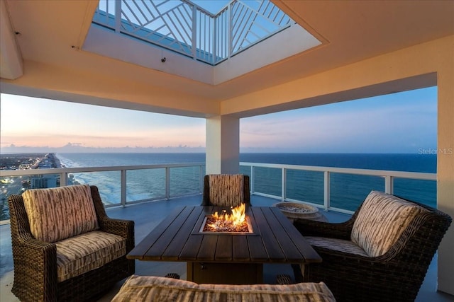 balcony at dusk with a water view and an outdoor fire pit