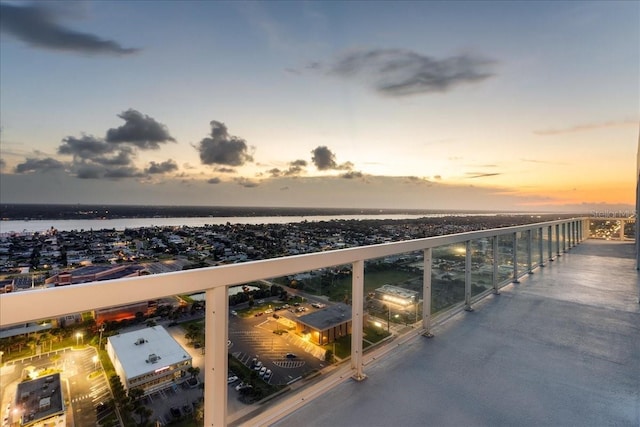 balcony at dusk featuring a water view