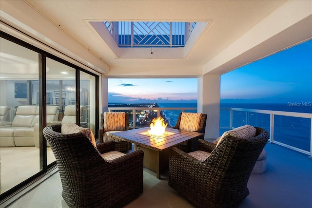 balcony at dusk with a water view and an outdoor living space with a fire pit