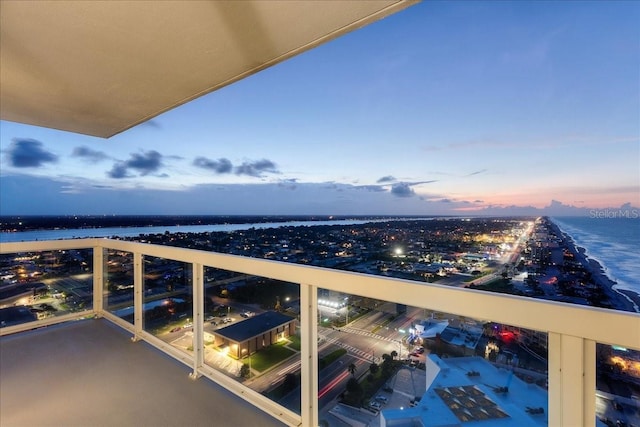 balcony at dusk featuring a water view