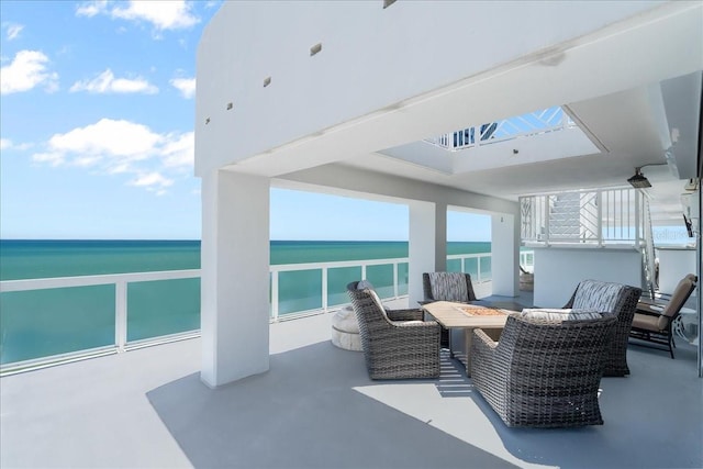 view of patio / terrace with a water view, a balcony, and an outdoor living space with a fire pit