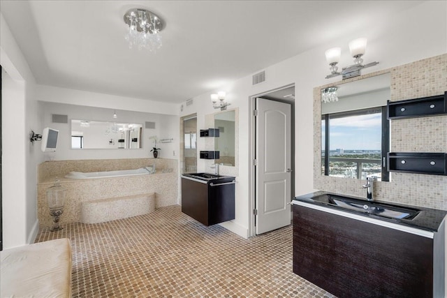 bathroom featuring tiled bath, backsplash, vanity, a notable chandelier, and tile patterned floors