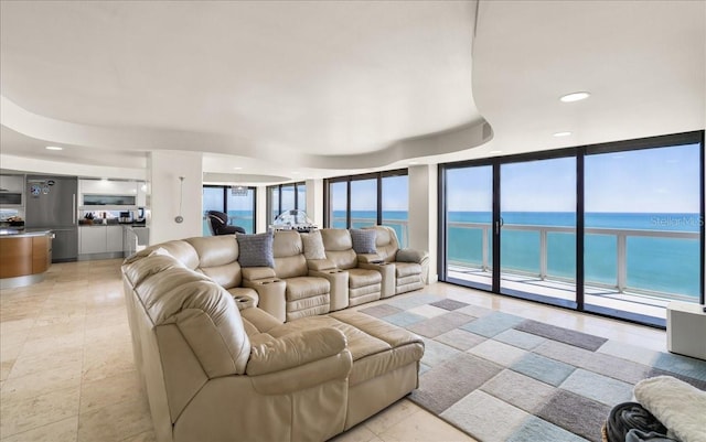 living room featuring a beach view, expansive windows, a healthy amount of sunlight, and a water view