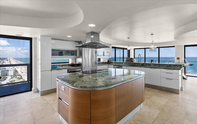 kitchen featuring a large island, pendant lighting, a water view, white cabinets, and island exhaust hood