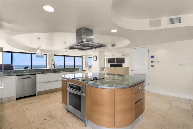 kitchen with island exhaust hood, appliances with stainless steel finishes, dark stone countertops, and white cabinets