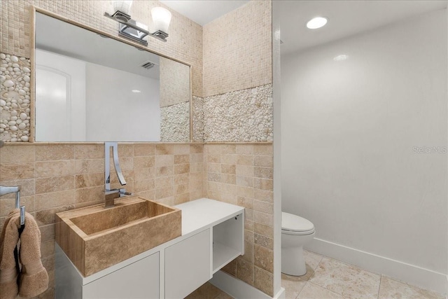 bathroom featuring tile patterned flooring, vanity, tile walls, and toilet