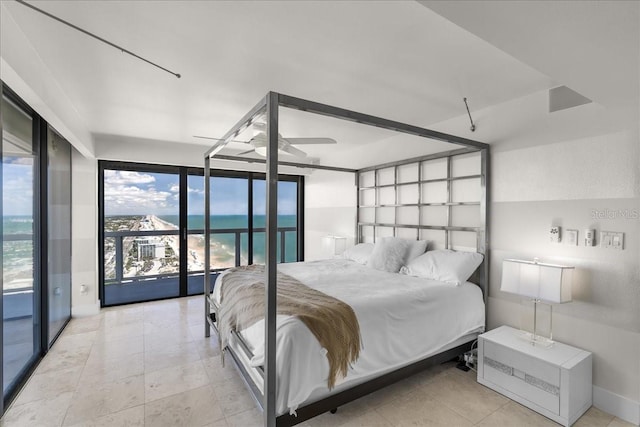 bedroom featuring access to exterior, expansive windows, and a water view