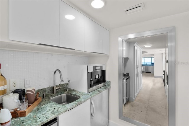 kitchen featuring tasteful backsplash, light stone countertops, sink, and white cabinets