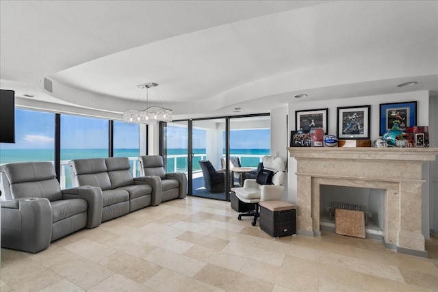 living room featuring a notable chandelier, a fireplace, and a water view