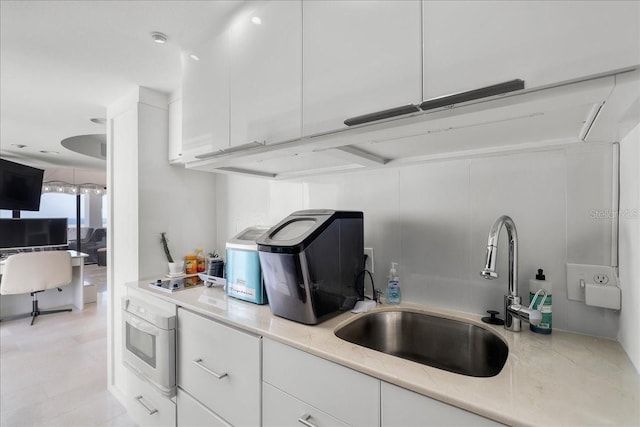 kitchen featuring black cooktop, white oven, sink, and white cabinets