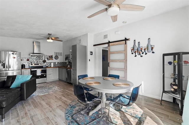 dining room with a barn door and ceiling fan